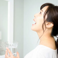 洗面所でうがいをする女性 口腔内を清潔に保つ習慣 歯科医院推奨ケア